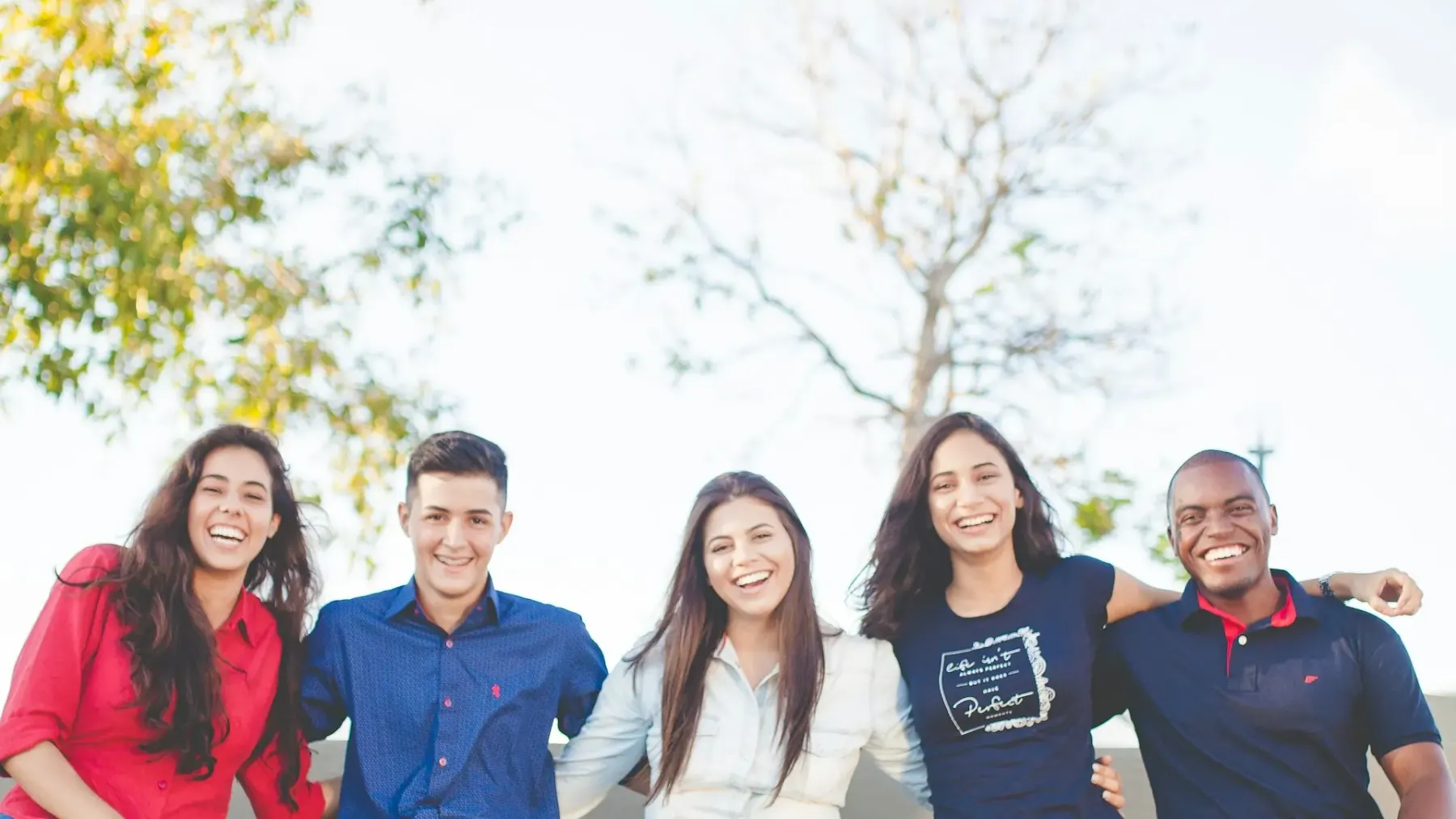 A group of young adults standing together outdoors, smiling